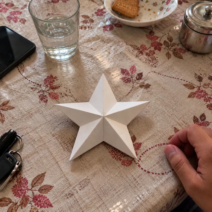 A white paper star on a patterned tablecloth